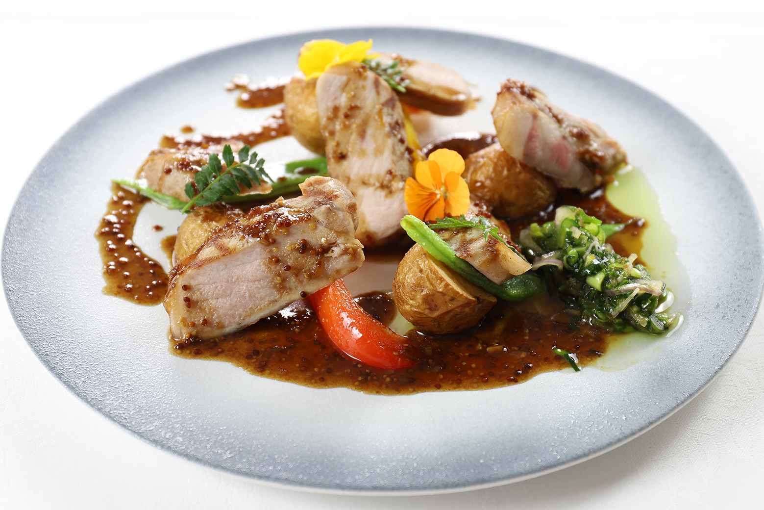 写真：京もち豚ロース肉のグリエ  韮とニンニクの芽のコンディモンを添え 蜂蜜と粒マスタードの甘酸っぱいソース ハーブの香りを纏わせたじゃが芋のフリットと共に
